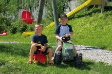 Kinder auf Spielzeugtraktor und Bobby-Car